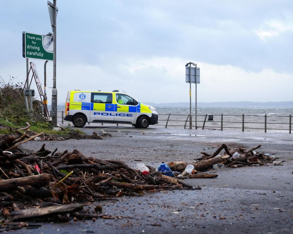 A police van blocks a Skelmorlie coastal road scattered with storm debris and driftwood