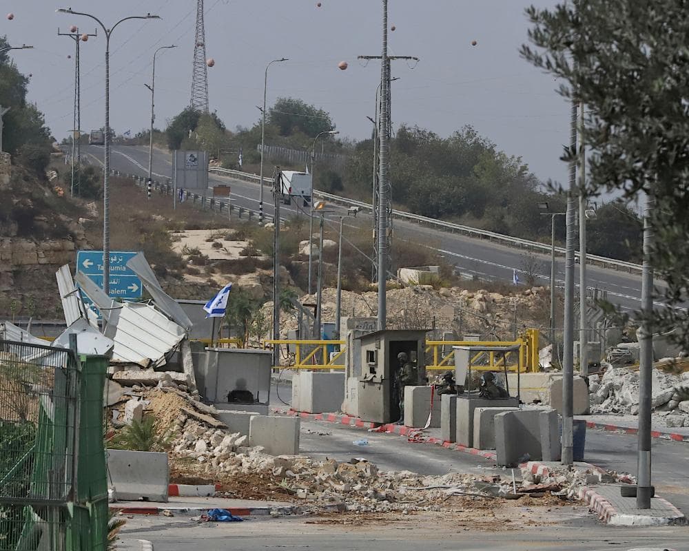 Soldiers stand at a checkpoint amid rubble near Hebron