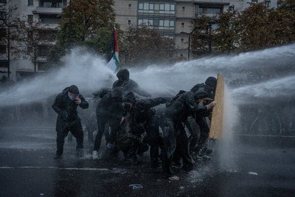 Protesters shielding themselves from a water cannon in Paris on Saturday.
